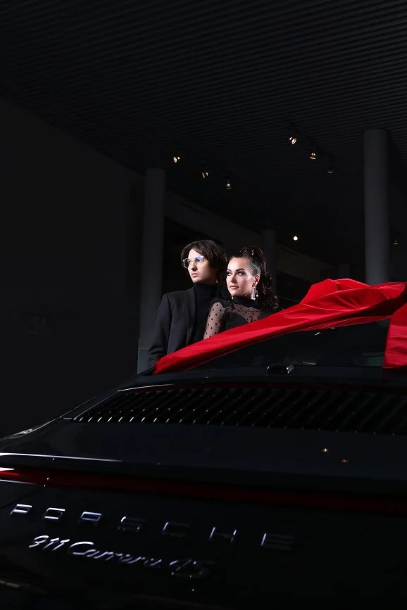 An editorial scene with a sports car and a red gown